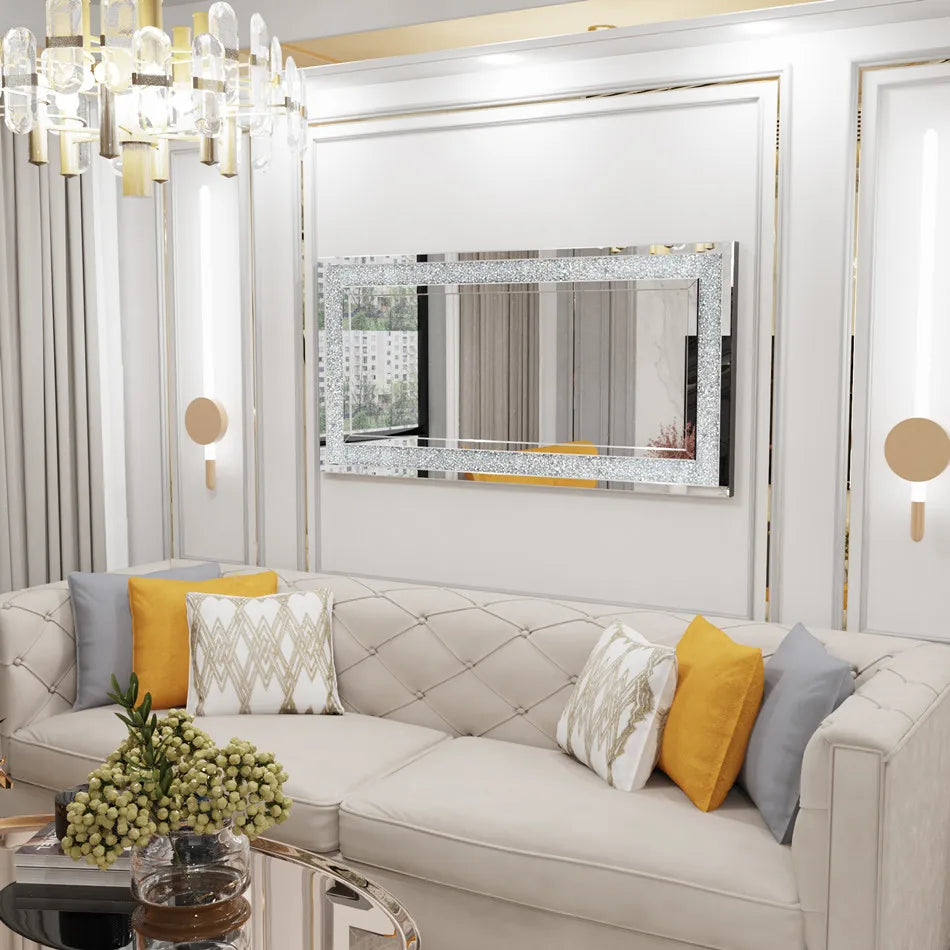 Un élégant salon moderne avec un canapé confortable, des coussins décoratifs, un miroir ornementé et un lustre en cristal, créant une atmosphère sophistiquée et chaleureuse.