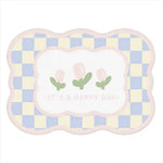 Tapis doux et coloré avec des motifs abstraits en forme de carrés, orné de fleurs vertes et portant l'inscription "It's a happy day".