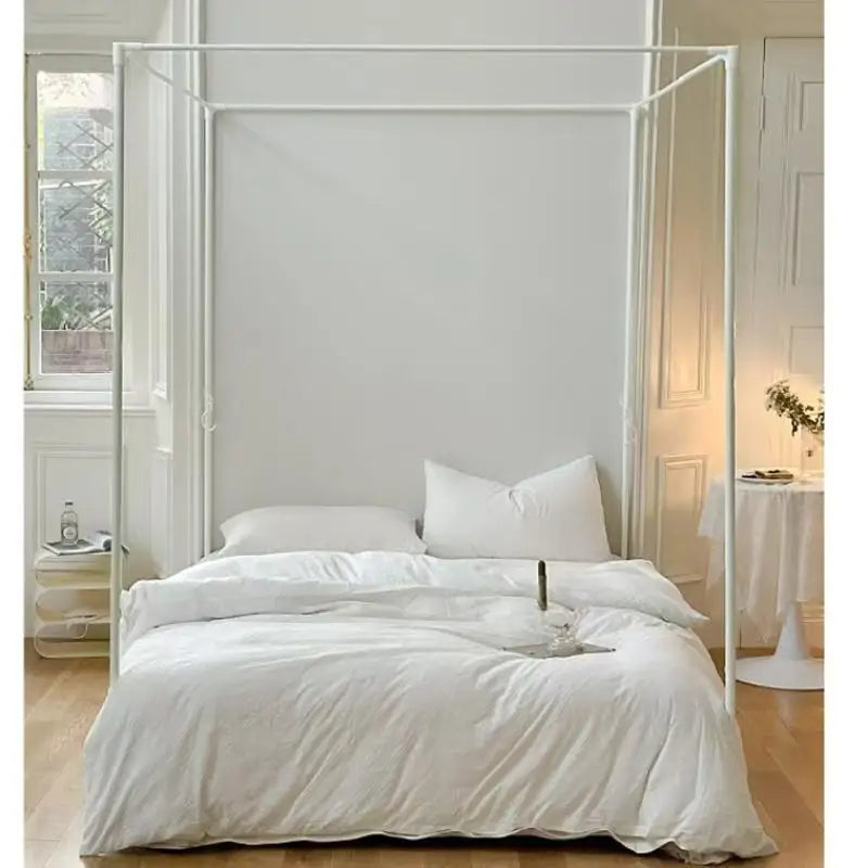 Lit à baldaquin élégant dans une chambre lumineuse et épurée, avec des draps blancs et un verre de vin sur un côté.