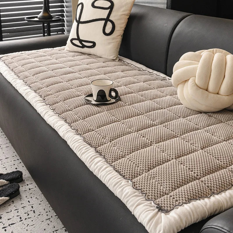 Tapis moelleux en fibres naturelles avec motif tressé, coussin décoratif et bougie sur un canapé en cuir noir, créant une atmosphère cocooning et confortable.