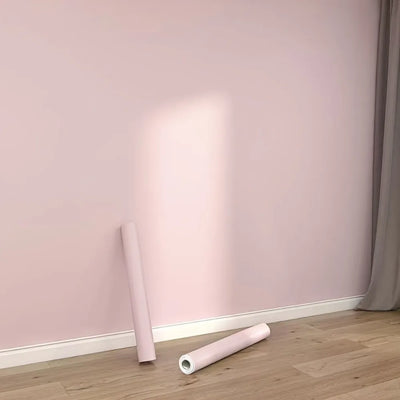 Papier peint adhésif étanche rose uni posé sur un mur de salon moderne