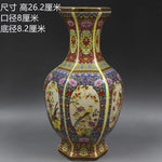 Vase décoratif de forme hexagonale en porcelaine, orné de motifs floraux colorés et d'oiseaux sur un fond doré.