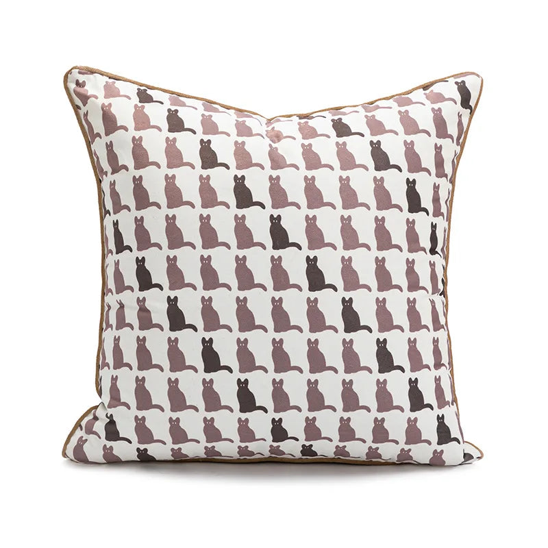 Coussin décoratif avec des silhouettes de chats imprimées dans des tons neutres, créant un motif répétitif et graphique.