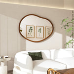 Salon élégant avec miroir mural ovale en bois, cadres décoratifs de feuillage et canapé blanc confortable.