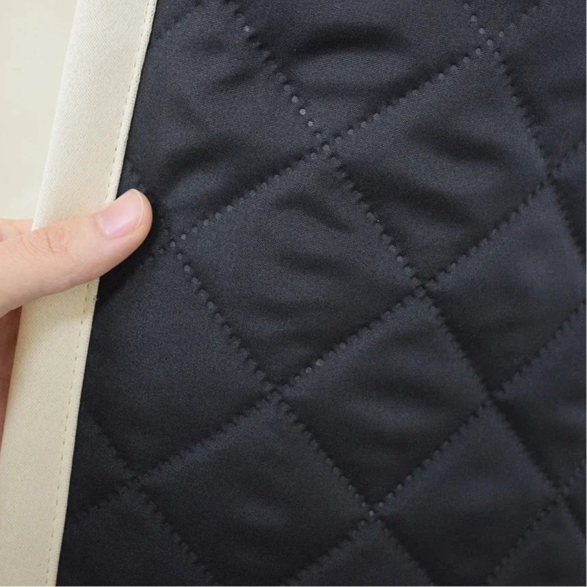 Image d'un détail de produit avec un motif matelassé noir. L'aspect visuel met en avant le design quadrillé, idéal pour ajouter une touche élégante et sophistiquée à votre intérieur. La finition soignée et le contraste des couleurs soulignent la qualité du produit. Parfait pour l'aménagement d'espaces modernes et stylés.