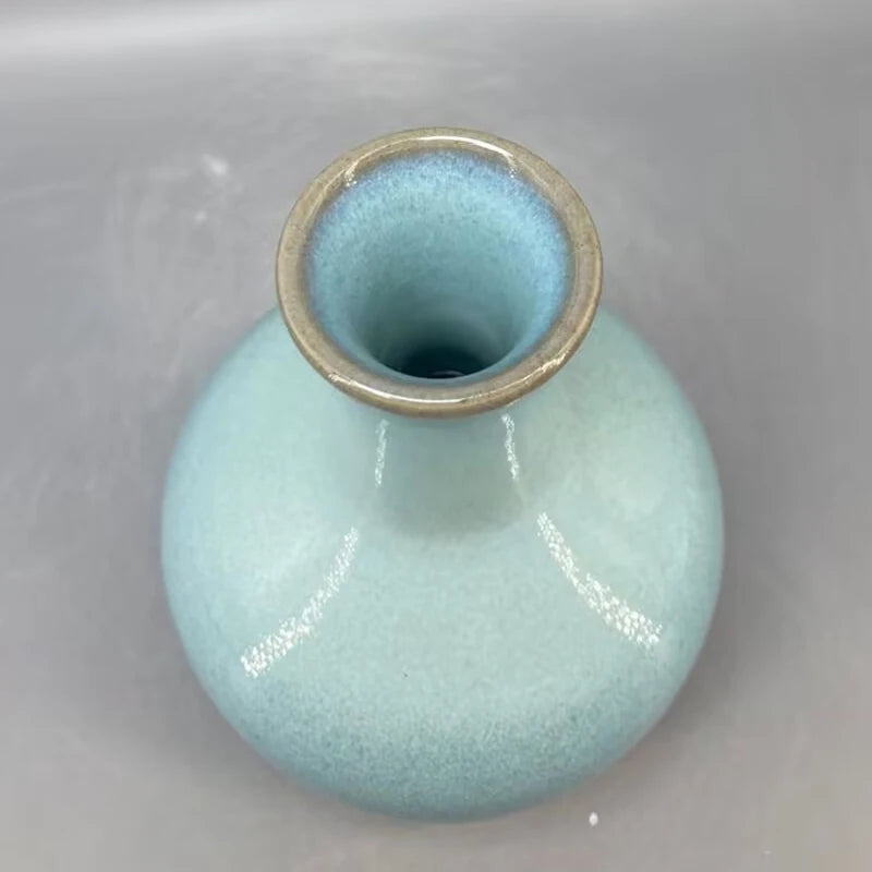 Un vase en céramique de couleur turquoise avec un col doré.