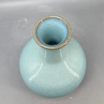 Un vase en céramique de couleur turquoise avec un col doré.