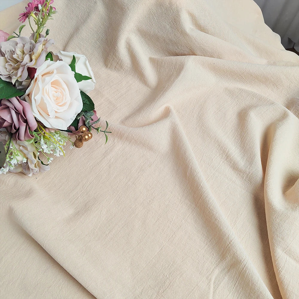 Cette image représente un bouquet de fleurs multicolores, notamment des roses délicates, posé sur une surface en velours beige.