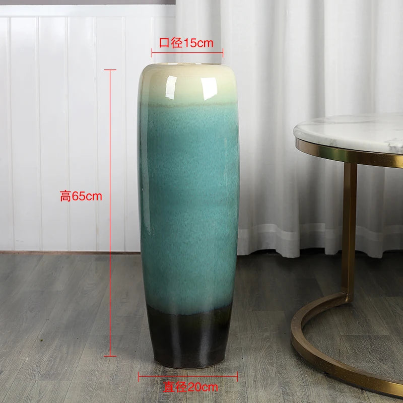 Un grand vase vert et noir élégant, d'une hauteur de 65 cm et d'un diamètre de 15 cm, posé sur un sol en bois sombre.