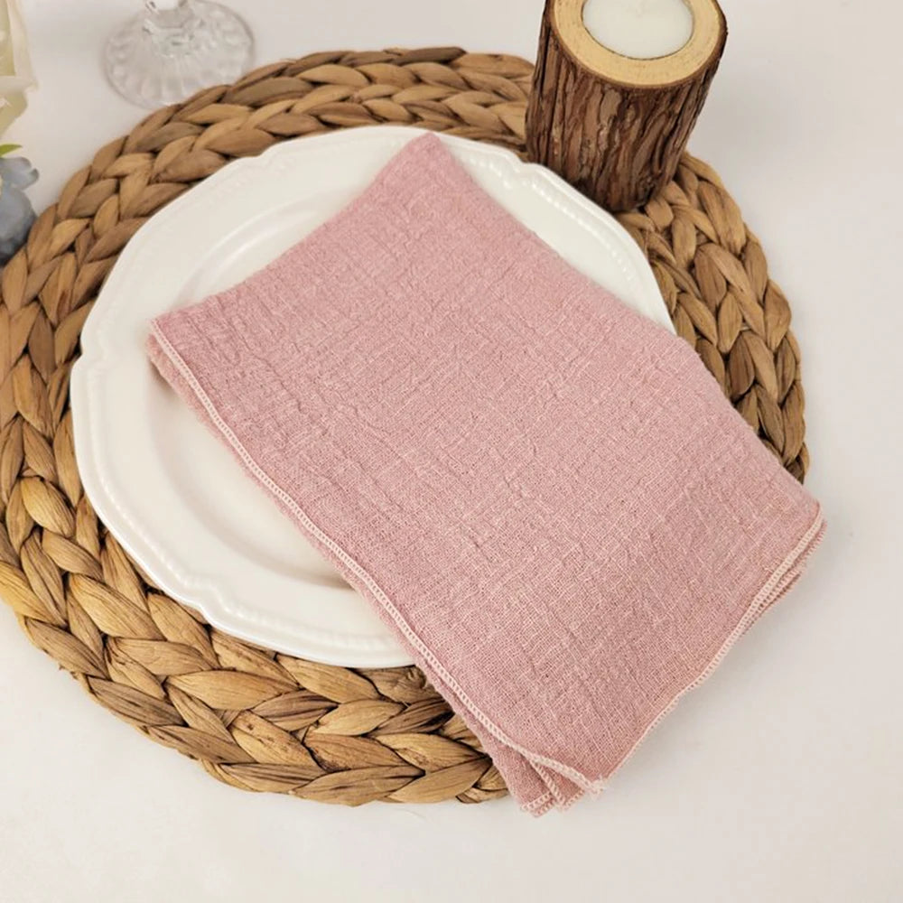 Un joli linge de table en lin rose pâle repose sur un plateau en osier tressé.
