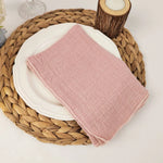 Un joli linge de table en lin rose pâle repose sur un plateau en osier tressé.