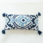 Coussin décoratif rectangle bleu marine et blanc, orné de motifs ethniques et de pompons.