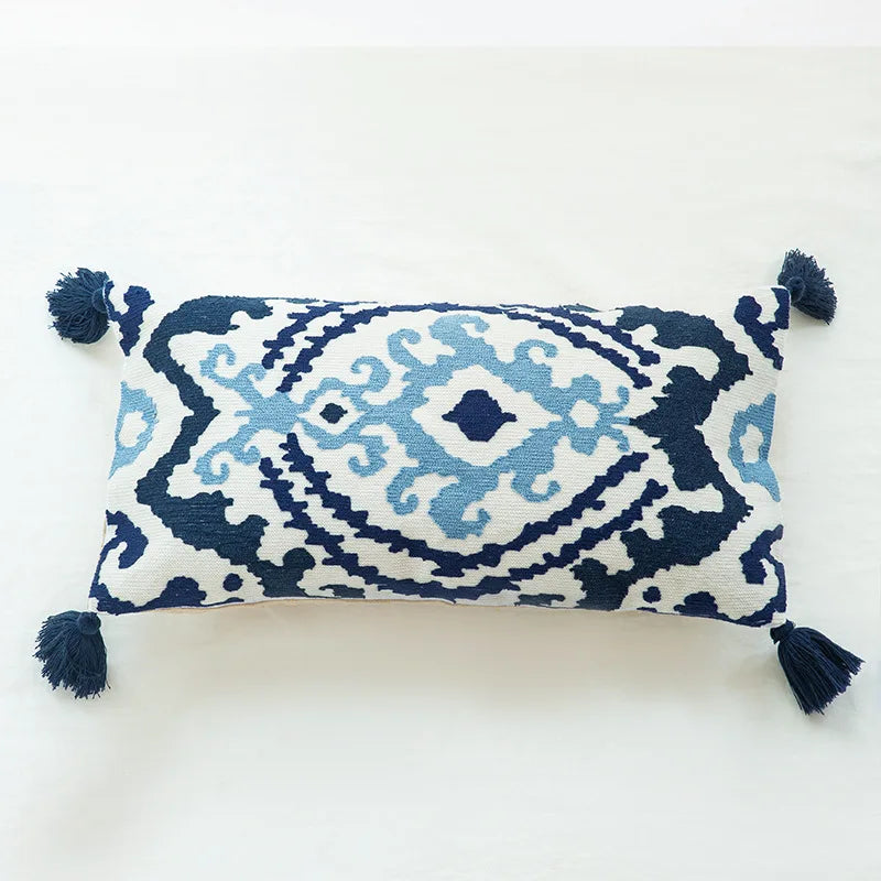 Coussin décoratif rectangle bleu marine et blanc, orné de motifs ethniques et de pompons.