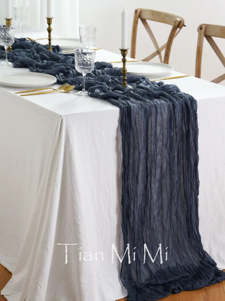 Une table élégante avec des bougies dorées, des verres en cristal et un chemin de table en tissu noir plissé, créant une ambiance chaleureuse et sophistiquée.