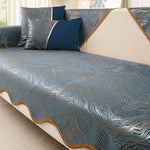 Cette image montre une couverture de lit aux motifs ondulés et texturés de couleurs bleues, grises et dorées, avec des oreillers assortis, créant une atmosphère élégante et sophistiquée pour une chambre.