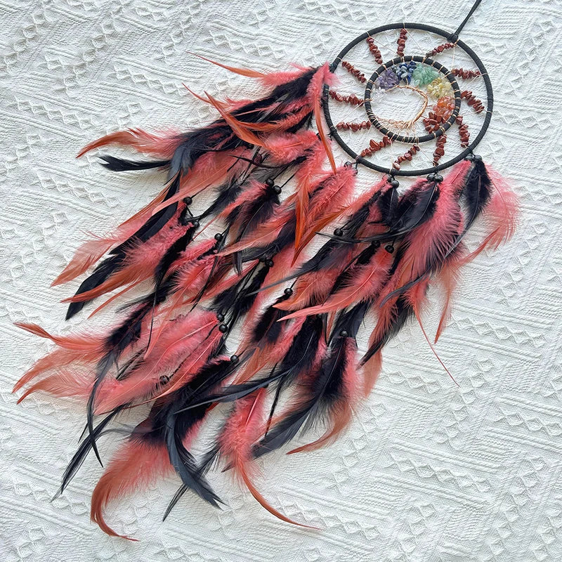Capteur de rêves décoratif en plumes rouges et noires suspendu sur un fond en dentelle blanche.