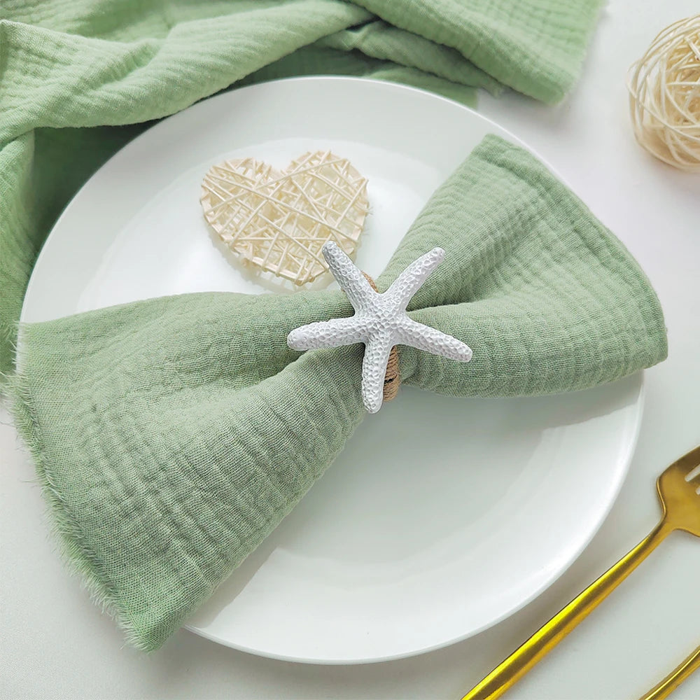 Une assiette blanche avec une serviette verte en lin et une décoration en forme d'étoile de mer.
