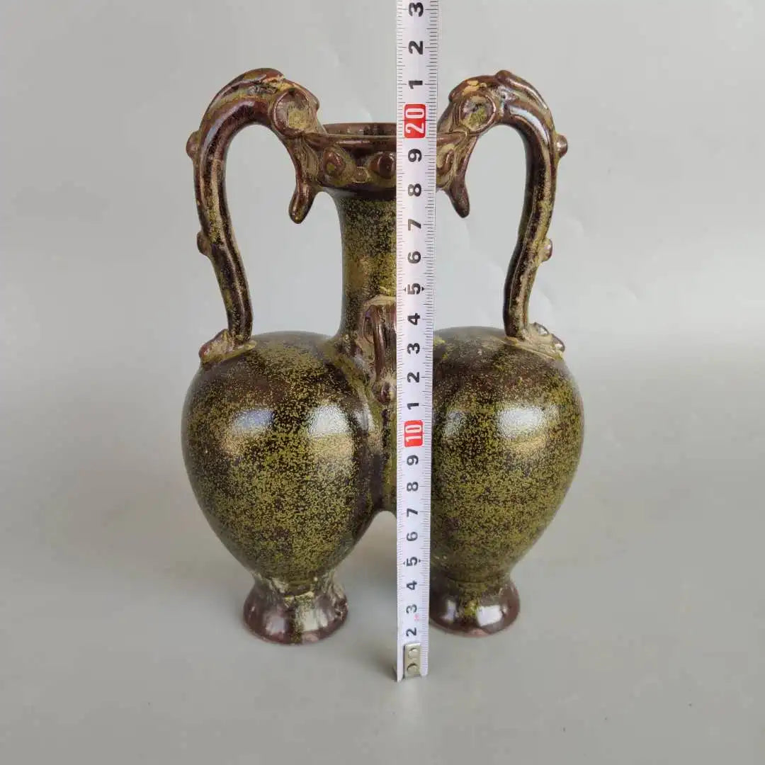 Deux vases décoratifs de forme ovoïde, avec des anses en forme de têtes d'animaux, recouverts d'un vernis craquelé aux teintes dorées et verdâtres.