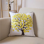 Coussin décoratif avec un arbre aux feuilles jaunes brodées sur un fond blanc, créant une décoration de salon chaleureuse et naturelle.