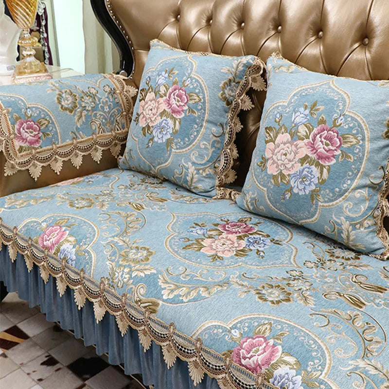 Canapé capitonné en cuir vieilli orné de coussins aux motifs floraux bleu et rose dans un style vintage luxueux.