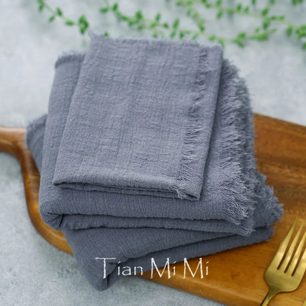 Des serviettes grises en tissu texturé, posées sur une surface en bois, avec le logo de la marque "Tian Mi Mi" visible.