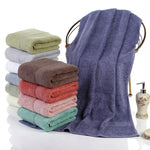 Grande serviette de bain 100% coton 70x140 cm épaisse et absorbante pliée sur un porte-serviettes en bois