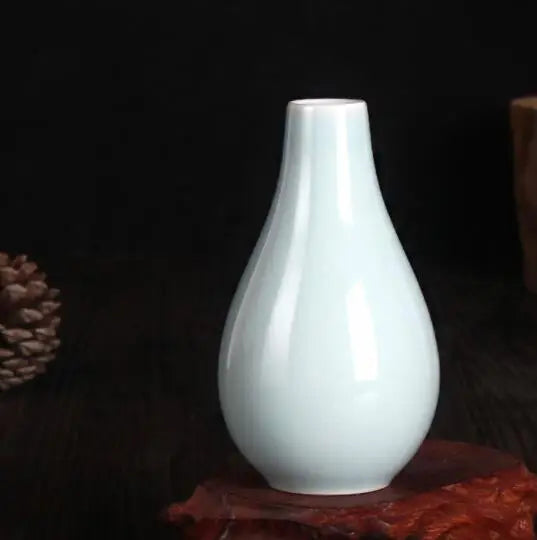 Vase blanc élégant et de forme unique, posé sur un fond sombre.