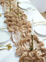 Table de banquet élégante avec nappe en voile crème, vaisselle blanche, verres en cristal et accessoires dorés, créant une ambiance sophistiquée et raffinée.