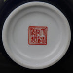 L'image montre un plat en céramique blanche avec un sceau imprimé en rouge contenant des caractères chinois.