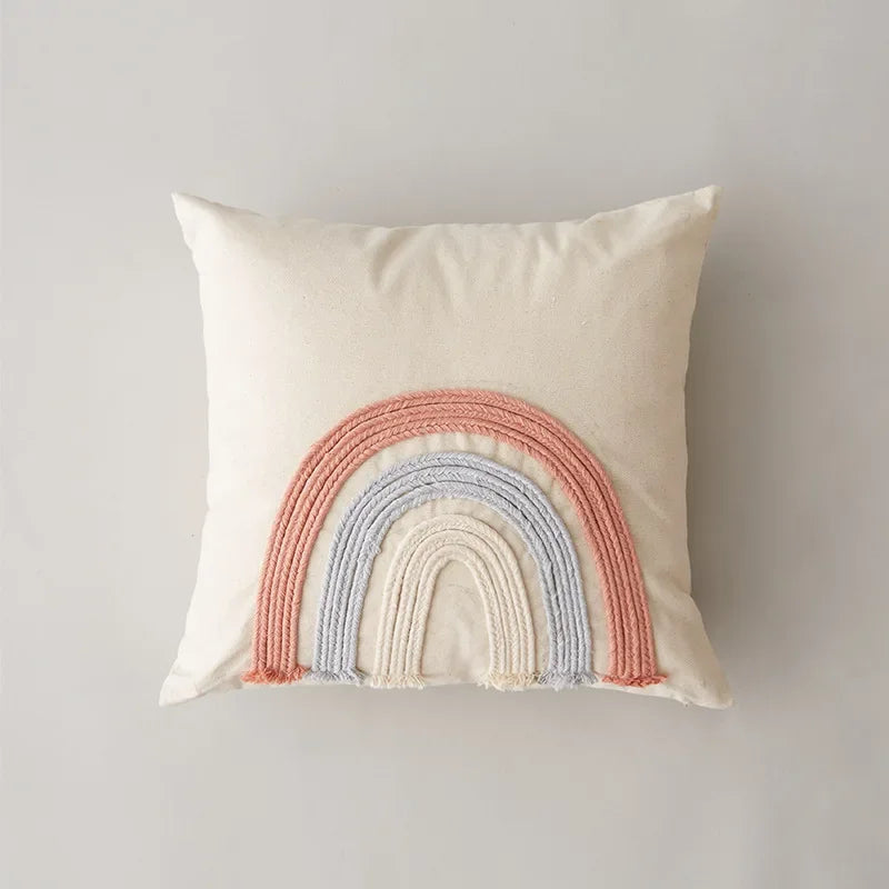 Coussin décoratif avec arc-en-ciel multicolore en corde tissée sur fond clair.