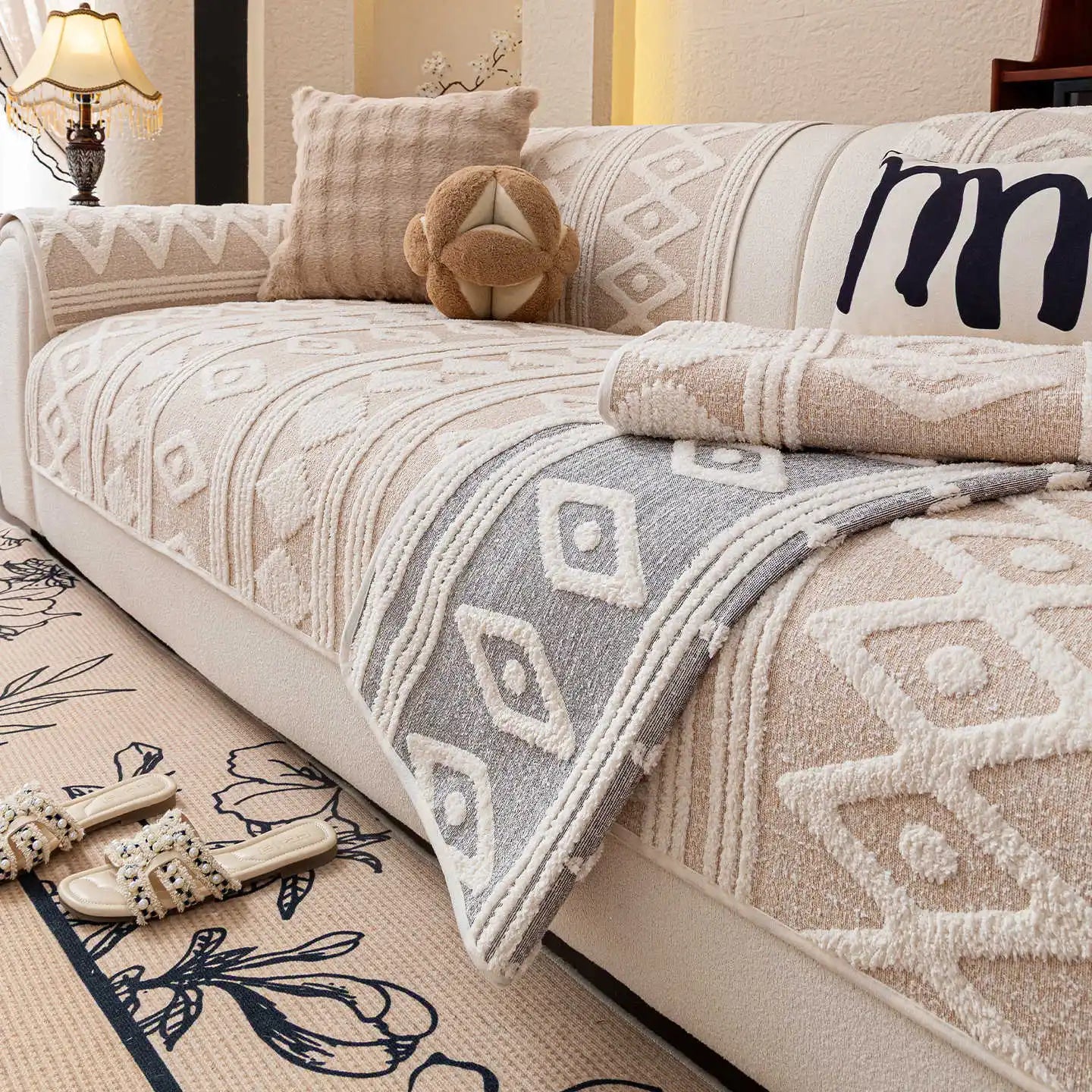 Le canapé est orné de motifs géométriques et de textures douces, créant une ambiance chaleureuse et accueillante dans cette pièce.