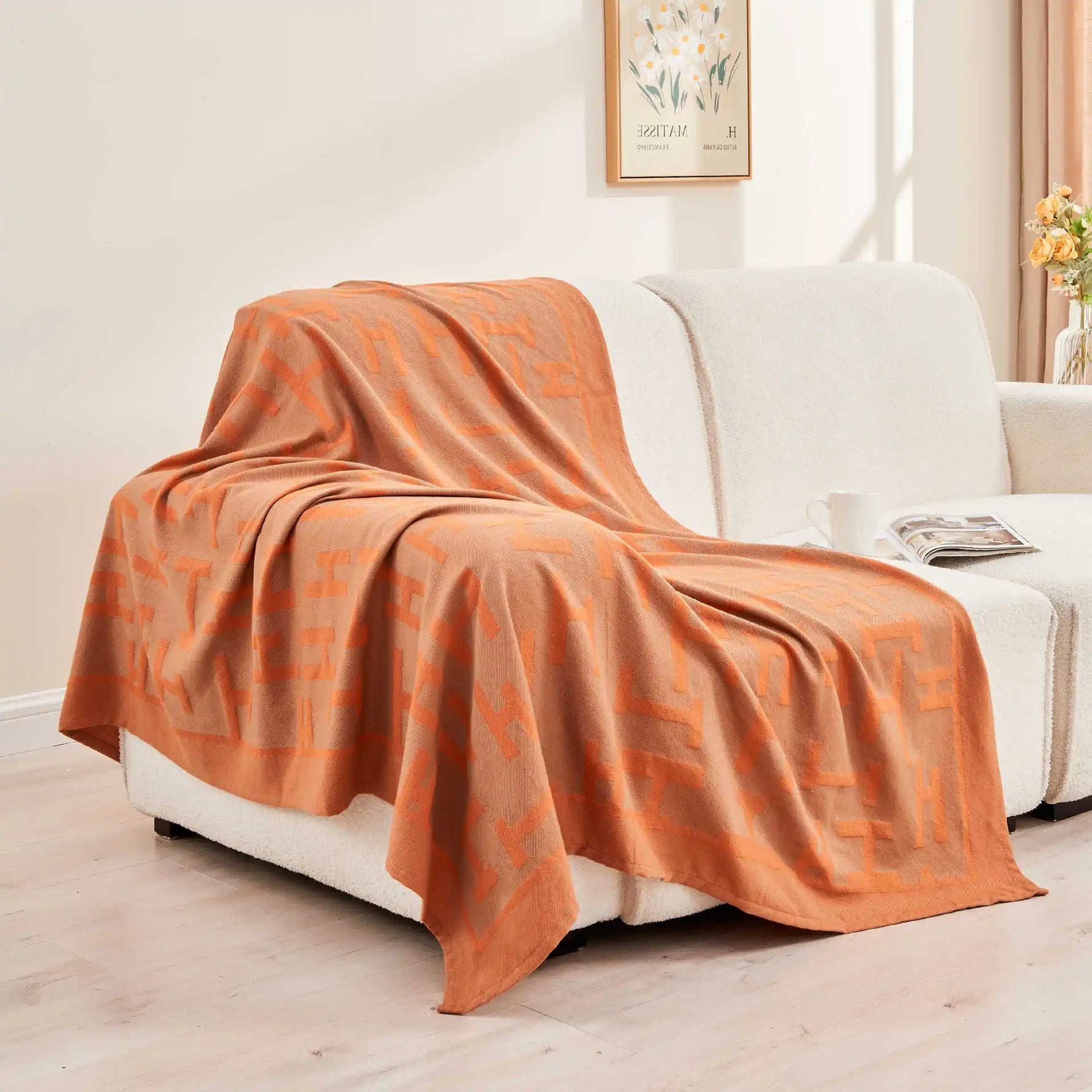 Une couverture en peluche orange et crème, posée sur un canapé blanc dans un salon élégant.