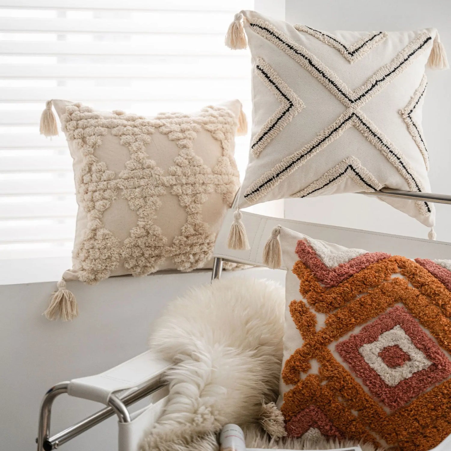 Une collection de coussins décoratifs avec des motifs géométriques et un coussin en fourrure blanche, créant une ambiance cosy et confortable dans la pièce.