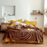 Chambre confortable avec des draps en velours marron et des coussins jaunes, créant une ambiance chaleureuse et accueillante.