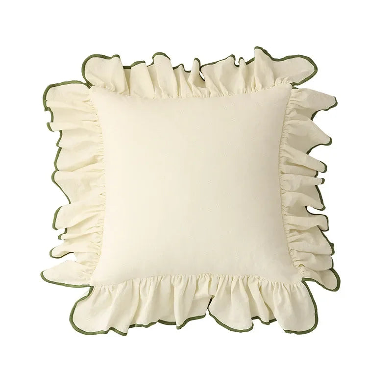Coussin décoratif blanc moelleux avec des détails de volants verts sur les bords, créant un aspect féminin et élégant.