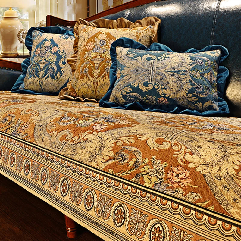 Un canapé élégant orné de motifs floraux dorés et bleus, avec des coussins assortis aux designs raffinés, créant une atmosphère de luxe et de sophistication dans la pièce.