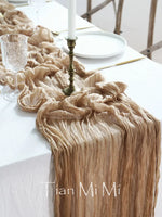 Un beau décor de table avec une nappe en tissu froissé de couleur beige, une assiette blanche, un chandelier en métal et un verre en cristal.