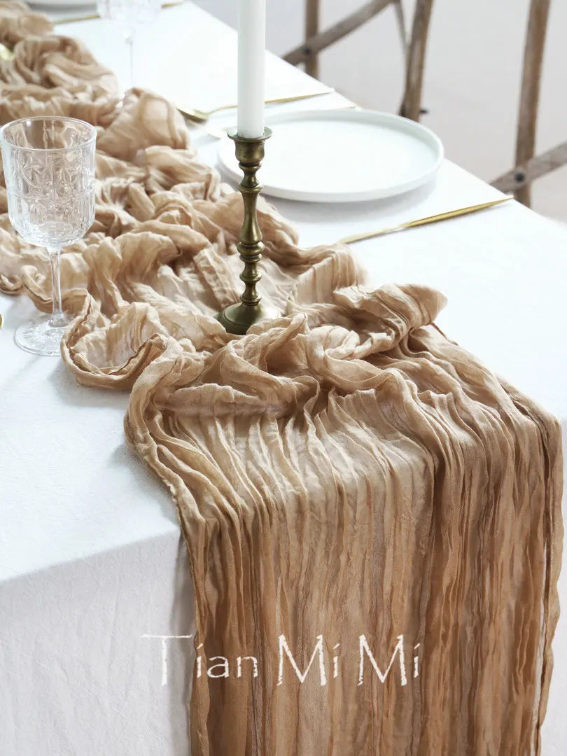 Un beau décor de table avec une nappe en tissu froissé de couleur beige, une assiette blanche, un chandelier en métal et un verre en cristal.