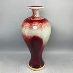 Vase en céramique de style vintage avec des touches de rouge et de blanc, présentant une texture et des motifs intéressants.