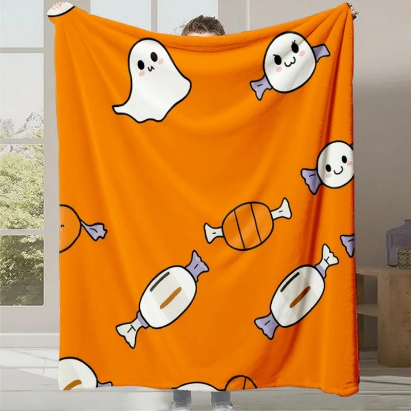 Une couverture en velours orange avec des fantômes et des bonbons mignons imprimés dessus, créant une atmosphère festive et amusante.