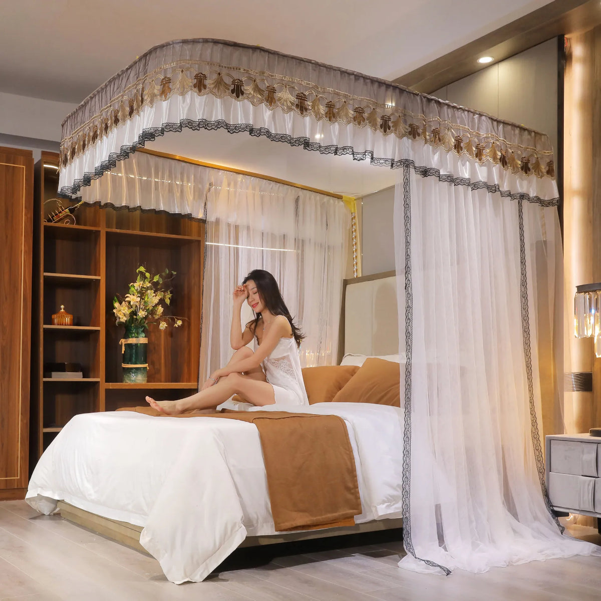 La chambre de style élégant arbore un lit à baldaquin drapé de rideaux blancs et de détails dorés, offrant un environnement relaxant et luxueux.