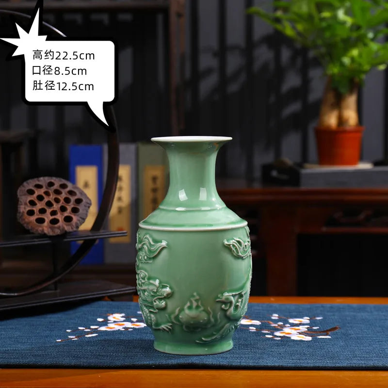 Un vase en céramique vert décoré de motifs de fleurs traditionnels sur un meuble en bois avec d'autres objets décoratifs en arrière-plan.