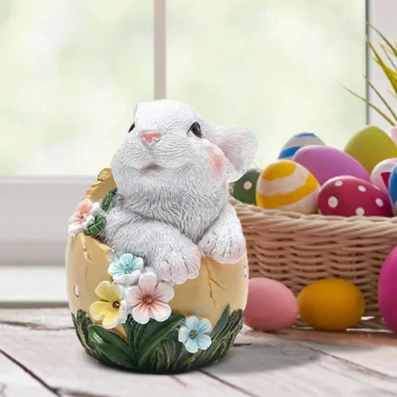 Un lapin gris mignon assis dans un œuf de Pâques décoré de fleurs colorées et posé sur une table en bois, entouré d'autres œufs de Pâques.
