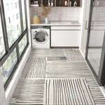 L'image montre une cuisine élégante et épurée avec un lave-linge, des étagères, et un sol carrelé aux motifs géométriques en noir et blanc.