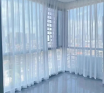 Rideaux en voile blanc sur baies vitrées d’angle avec vue sur la ville