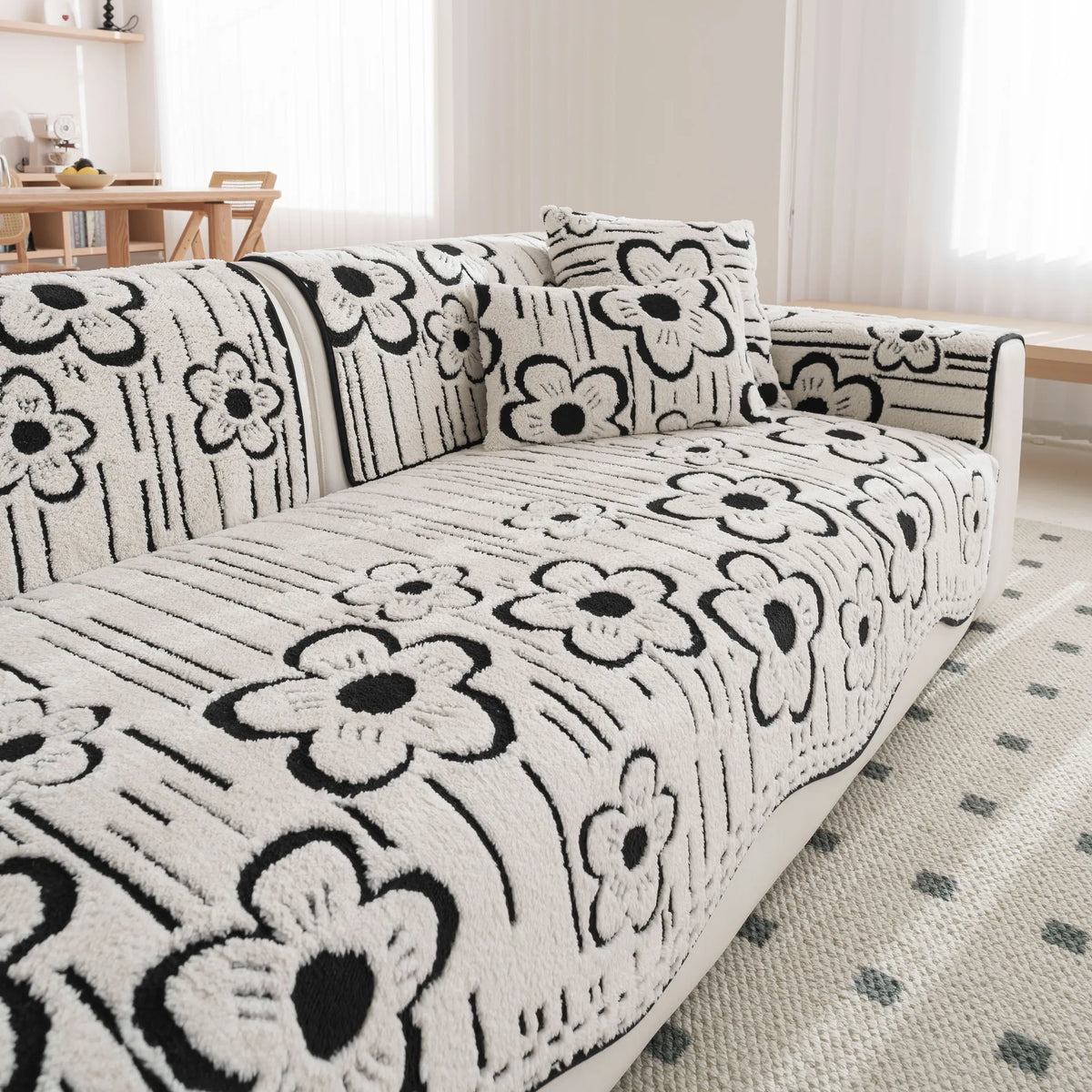 Canapé moelleux avec un motif floral noir et blanc, créant une ambiance élégante et chaleureuse dans le salon.