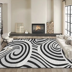 Tapis noir et blanc géométrique avec motif tourbillonnant, situé dans un salon moderne avec cheminée et mobilier épuré.