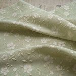 tissu brodé fleurs blanches vert clair beige polyester largeur 140cm opacité résistance intempéries respectueux