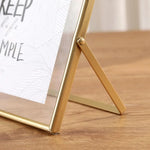 cadre photo moderne minimaliste or noir pieds triangulaires texte simple verre