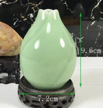 Une élégante vase en céramique de couleur vert pastel, avec des dimensions indiquées.